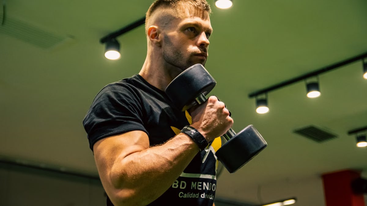 A man intensely lifting dumbbells indoors, showcasing strength and determination.